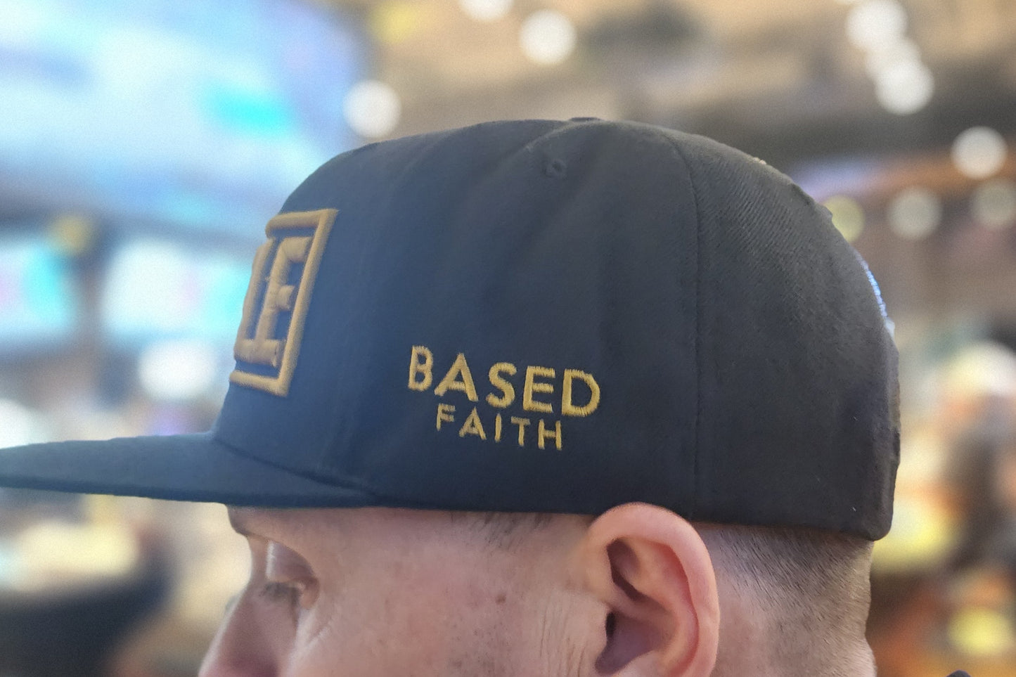 Person wearing a blue cap with 'BASED ON FAITH' text in an indoor setting
